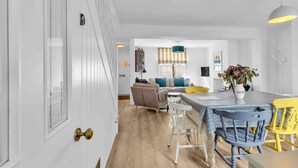 A modern kitchen with white cabinetry, a dining table with a patterned tablecloth, and a yellow chair. - Mill Cottage | By My Getaways (Brighton)