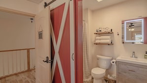 Ein Badezimmer mit Toilette, Waschbecken, Spiegel und Duschvorhang.