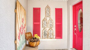 Eine rote Holztür mit floralen Verzierungen und ein Korb mit Tannenzapfen und Blumen.