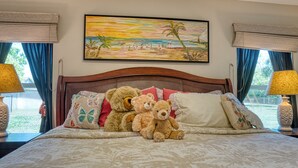 Ein Schlafzimmer mit einem Bett, Kissen und einem Bild von einer Strandansicht.