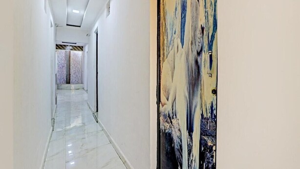A hallway with a marble floor, a door with a number, and a patterned wall. - Hotel Sarovar Inn (Ahmedabad)