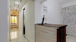 A hallway with a reception desk, a door, and a wall-mounted electrical panel. - Hotel Sarovar Inn (Ahmedabad)