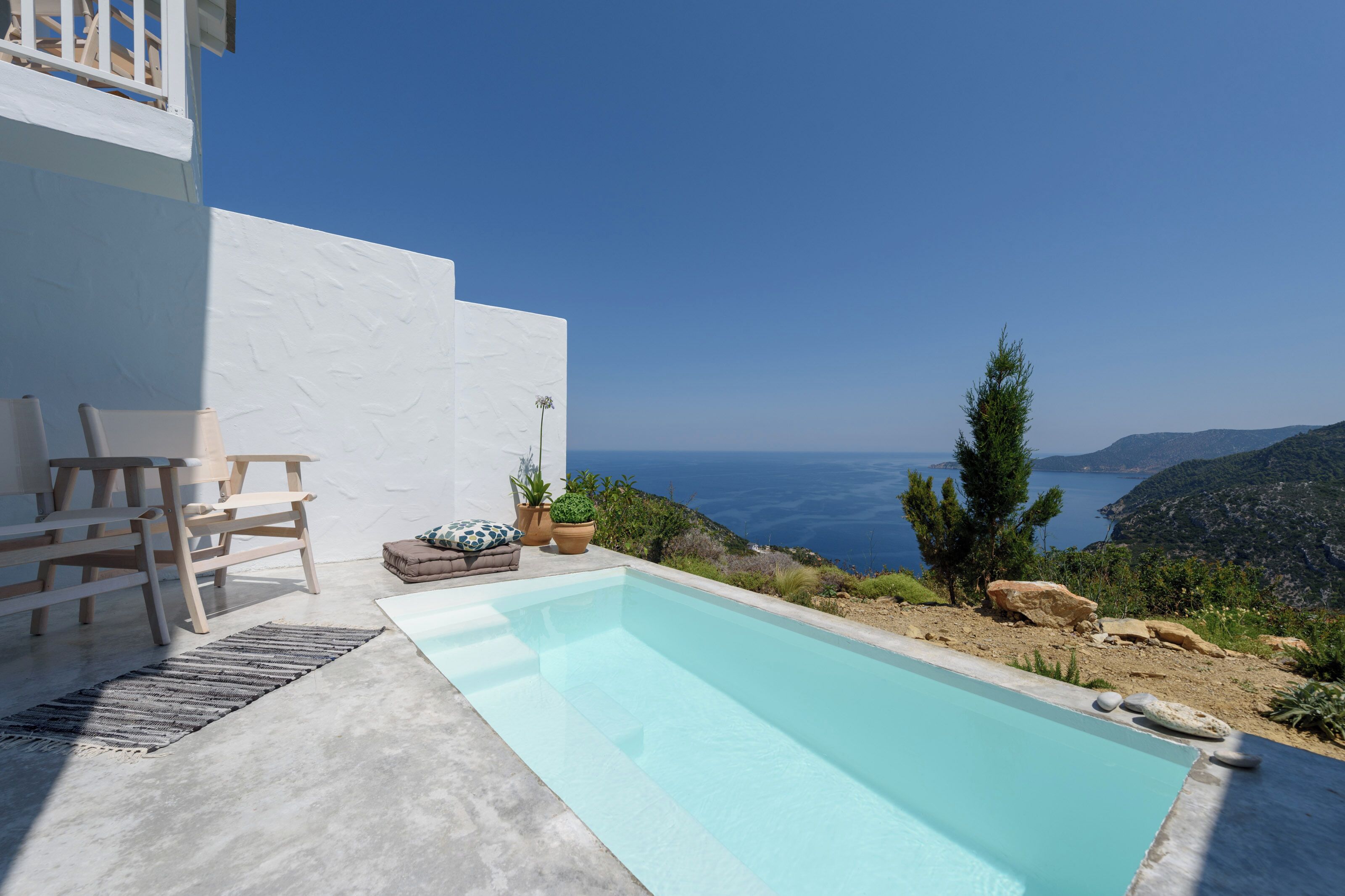 Ein Poolbereich mit Meerblick, ein weißes Gebäude und Gartenmöbel.