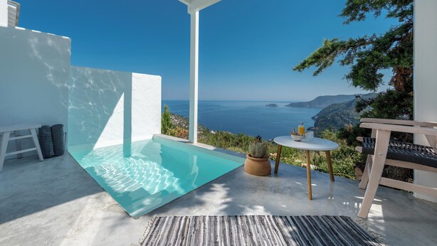 A modern outdoor pool area with a clear view of the sea and mountains.