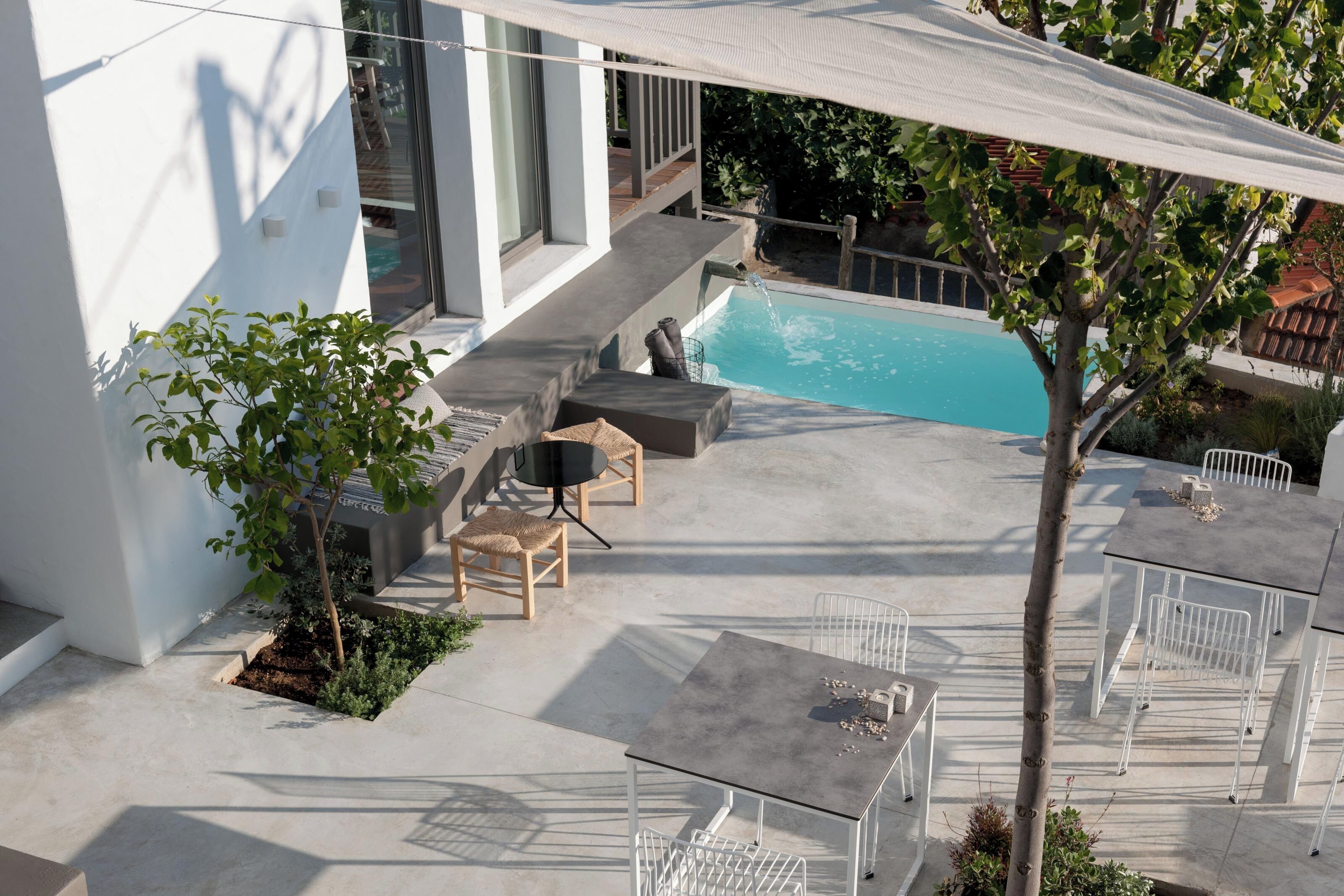 A modern outdoor patio with a pool, seating area, and a table.
