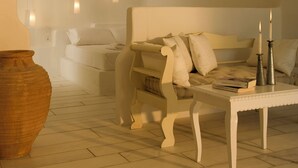 A minimalist living room with a white sofa, a coffee table, and two candles.