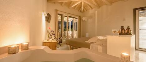 Un cuarto de spa con techo de madera, una bañera, una cama y una mesita con velas.