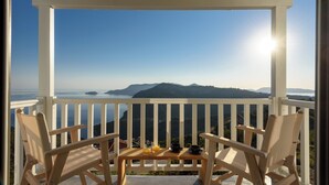 A wooden deck with two chairs and a table, overlooking a mountainous landscape with a clear sky.