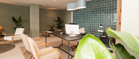 Un espacio de oficina moderno con un escritorio, sillas, una computadora y plantas en macetas.