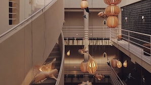 A modern interior with a central staircase, multiple hanging spherical light fixtures, and a glass ceiling allowing natural light. - Atlante Sanxenxo Boutique (Sanxenxo)