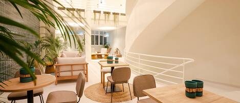 A modern interior with a round dining table, several chairs, and a staircase with a white railing.