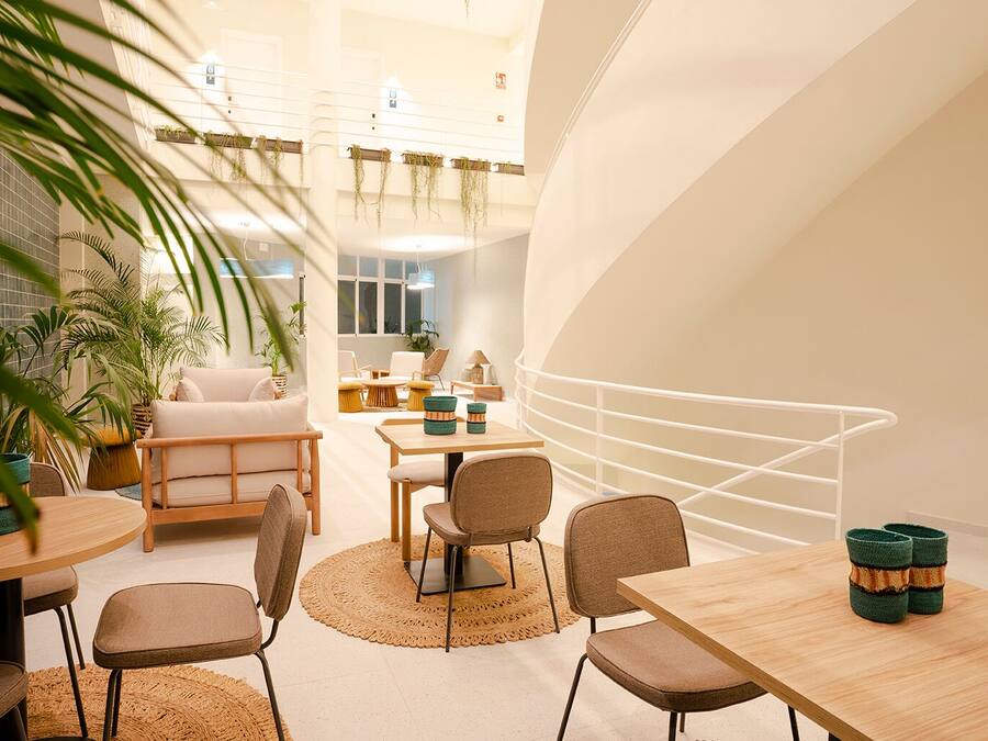 A modern interior with a round dining table, several chairs, and a staircase with a white railing.