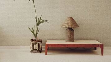 A wooden table with a woven lamp beside a textured wall.