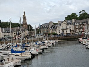 A marina with multiple boats docked, a prominent tower, and residential buildings in the background.
