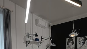 A modern living room with a red sofa, a small round table, and a white dining table. There is a kitchen area with white cabinets and a black backsplash. - Cracow Fancy Brick #3 – Old Town (Kraków)