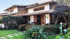 Una casa de dos pisos con fachada de piedra, techo de tejas y un jardín cuidado con piedras para caminar y plantas en flor.