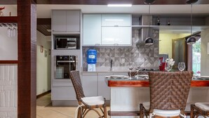 Una cocina moderna con electrodomésticos integrados, un comedor con sillas de mimbre y un dispensador de agua azul.
