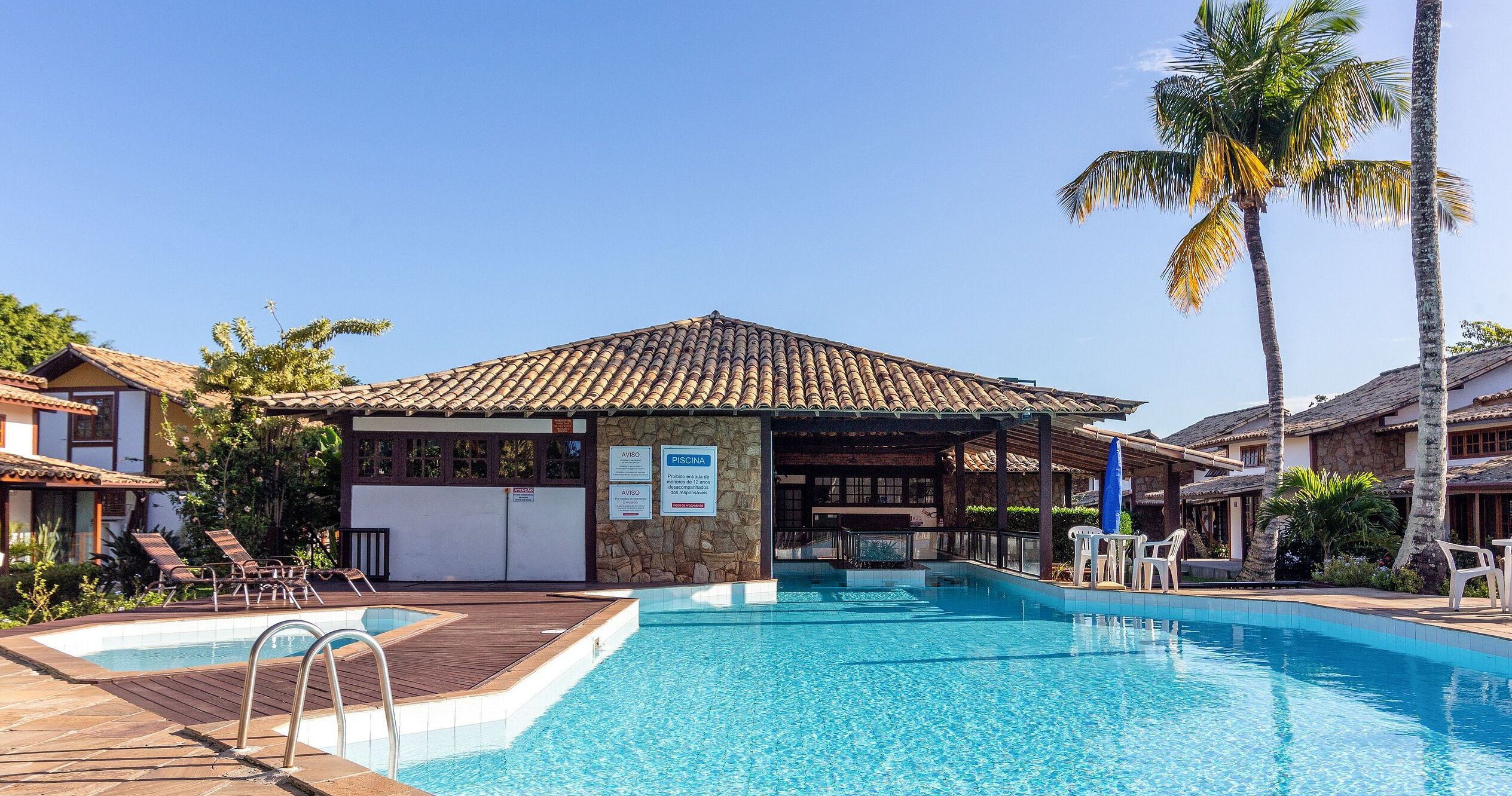Una piscina al aire libre, sillones reclinables de piscina