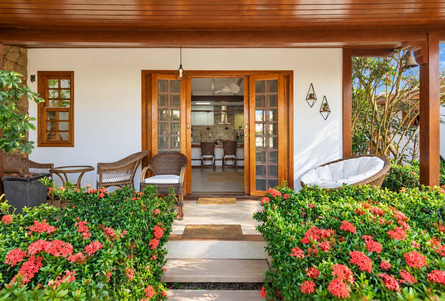 A covered outdoor area with wicker furniture, a dining table, and a white chair.