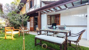 Un patio con mobiliario de mimbre, una mesa de comedor y sillas.