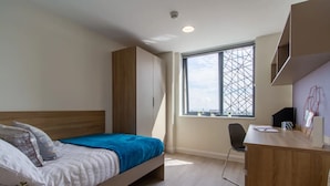 A modern bedroom with a bed, a desk, and a window with a view. - For Students Only Skyline (Bournemouth)