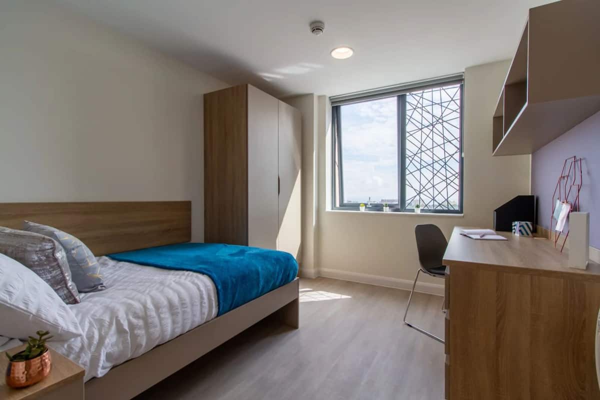 Ein modernes Schlafzimmer mit Bett, Schreibtisch und Fenster mit Blick.