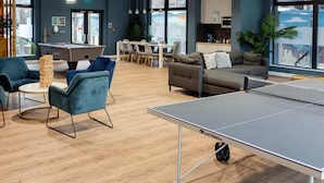 A modern indoor space with a ping pong table, seating area with sofas and chairs, a pool table, and a kitchen area. - For Students Only Skyline (Bournemouth)