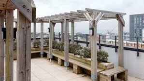 A rooftop terrace with wooden pergola, seating, and planters. - For Students Only Skyline (Bournemouth)