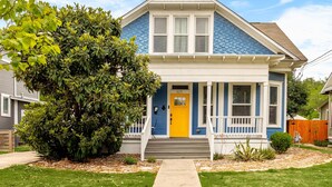 A two-story house with a blue exterior and a yellow front door. - La Flor: Family Dream Home ~ .5mi to Pearl ~ Pool (San Antonio)