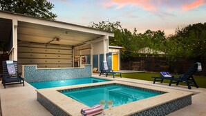 A swimming pool with a tiled deck, lounge chairs, and a covered area with a door. - La Flor: Family Dream Home ~ .5mi to Pearl ~ Pool (San Antonio)
