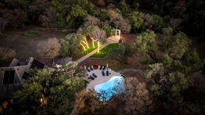 An aerial view of a residential property with a swimming pool, outdoor seating area, and a well-lit pathway.