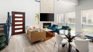 Ein modernes Wohnzimmer mit Kamin, einer Couch, einem Couchtisch und einem an der Wand montierten Fernseher.