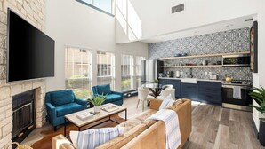 Ein modernes Wohnzimmer mit Kamin, Flachbildfernseher und einer Küche mit gemustertem Fliesenspiegel und eingebauten Geräten.
