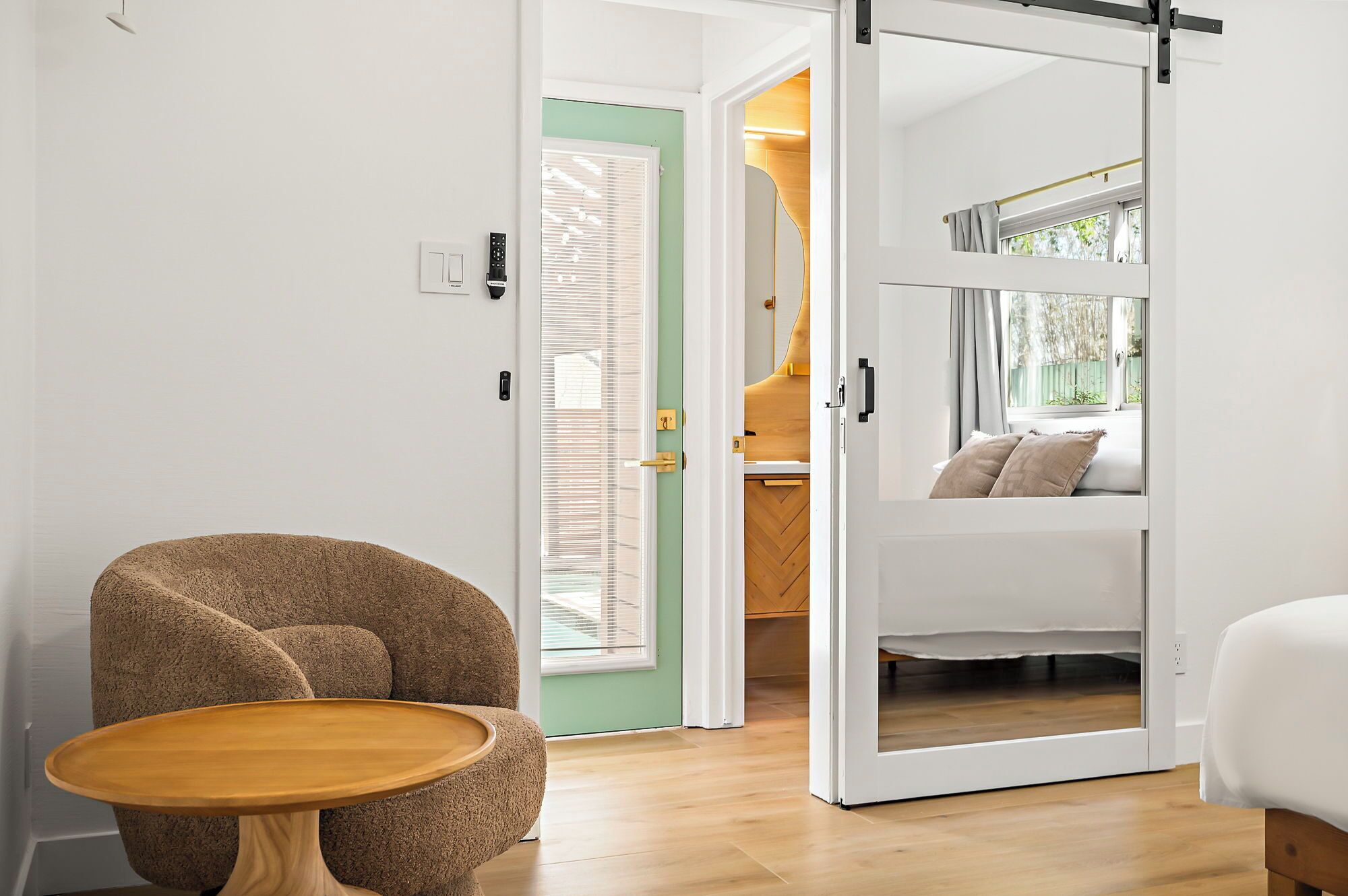 A modern interior with a sliding door leading to a balcony, a round wooden table, and a cozy seating area with cushions.