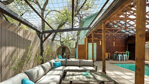 A covered outdoor seating area with a pool, wooden pergola, and a view of a house. - Haven de Luz: A Tranquil Retreat ~ Pool|Spa|Sauna (Austin)