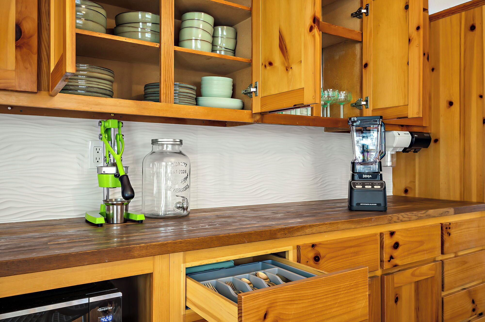 A kitchen with wooden cabinets, a blender, a juicer, and a dishwasher.