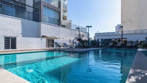 En modern inomhuspool med kristallklart blått vatten, omgiven av en betongplattform och en byggnad med balkonger.