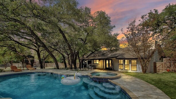 Un jardin avec une piscine, un jacuzzi et un espace patio couvert.