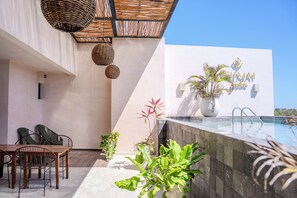 A modern outdoor area with a pool, dining table, chairs, and potted plants. - The Garden Residences by Casago (Tulum)