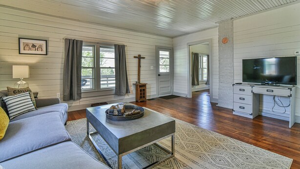 A spacious living room with a sofa, coffee table, and TV stand. - The Spruce House Cozy Home in Swannanoa (Swannanoa)
