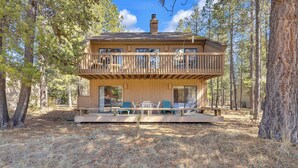 Eine Holzhütte mit Balkon, Sitzgelegenheit im Freien und Blick auf den Wald.