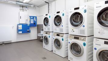 Een wasserette met meerdere witte wasmachines, een blauw bedieningspaneel en een wasbak.
