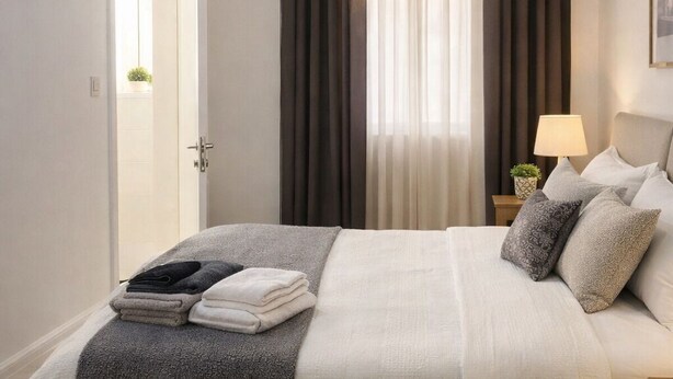 A bedroom with a bed, a bedside table, a lamp, a window with curtains, and a door. - Charming 2-bedroom apartment with Valley Views in Kerċem (Kercem)