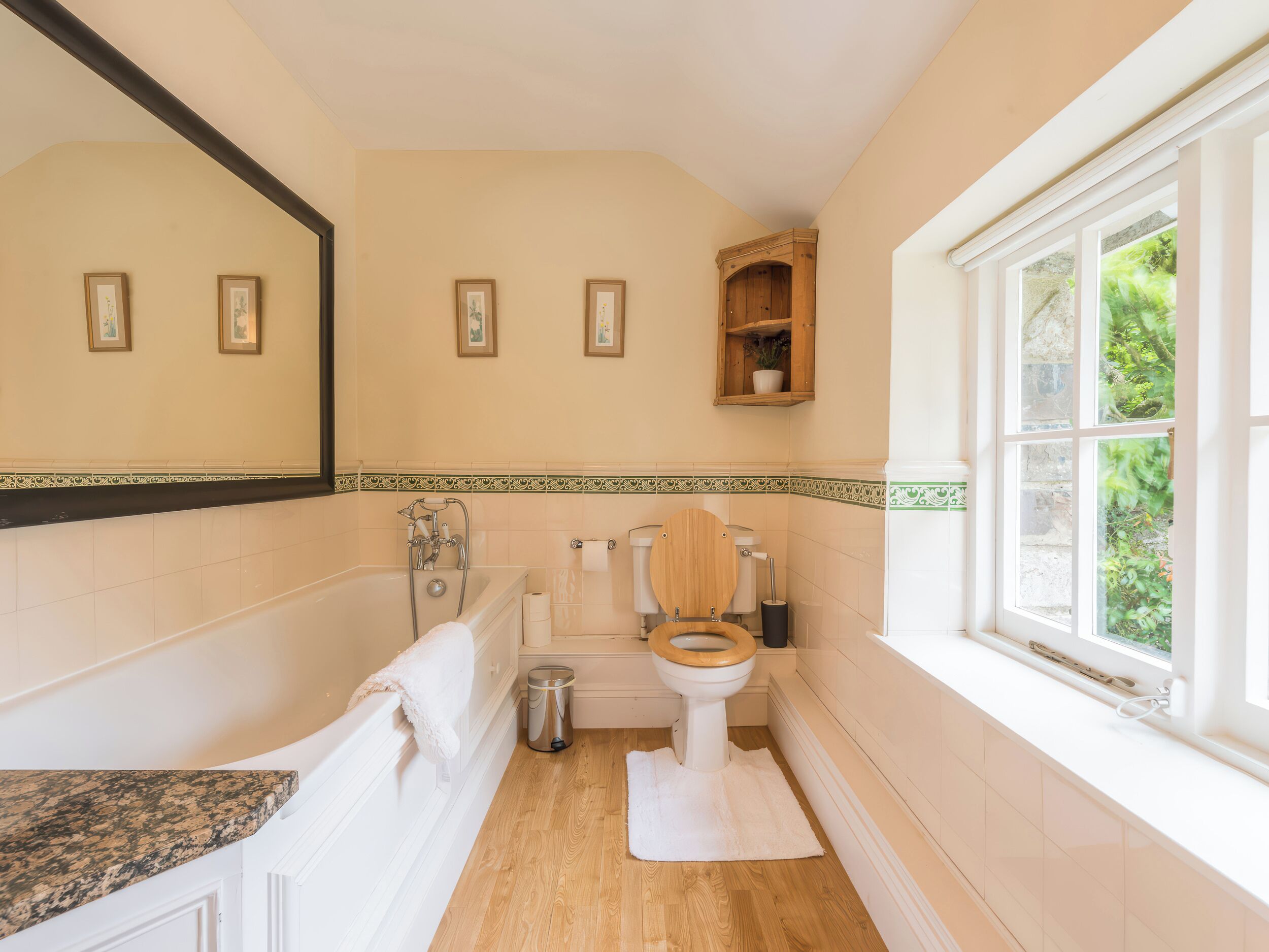 A bathroom with a bathtub, toilet, and window.