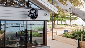 Un restaurant avec une enseigne indiquant « KYST » et, en arrière-plan, une vue sur un pont.