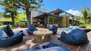 Zona d'estar exterior moderna amb seients de bolla i una xemeneia de pedra, amb vistes a una piscina i una casa contemporània.