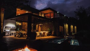 Una casa moderna amb piscina, zona d'estar a l'exterior i una llar de foc.