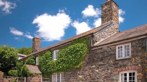 A stone building with ivy-covered walls, a wooden beam structure, and a brick chimney.