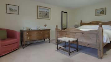 A bedroom with a wooden bed, a wooden dresser, a red sofa, and three framed pictures on the walls.