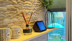 A shelf with a diffuser, a digital clock, and decorative items. - Charming Cottage on the São Roque Wine Route - Design and Nature in the Mountains (São Roque)